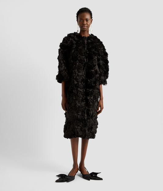 A statement coat from Erdem. A black textured coat made from pure silk covered in 3D roses. The statement coat has a loose-fit silhouette with a crew neck and elbow length sleeves. Perfect to wear over an evening gown. 