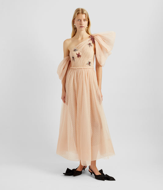 A drape detail tiered dress made from pink tulle with an asymmetric bodice. The flared tulle skirt is perfectly balanced with large sleeves and embellished bug brooches. 