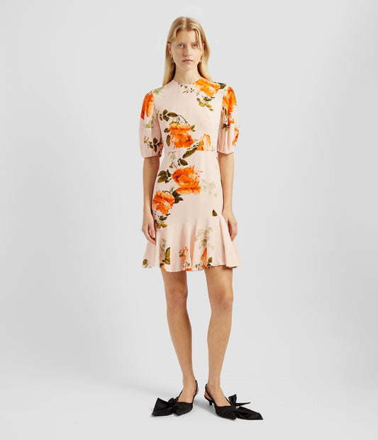 A short sleeve dress with voluminous sleevs and a tiered skirt. The short fit and flare dress is made from pale pilk silk crepe with a large orange rose print. 