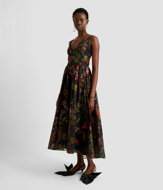A v neck fit and flare dress by designer Erdem. The midi evening dress is sleeveless with a fitted bodice, waista and then a large volumous flared skirt. The dress is made from black organza with red and pink floral print. 