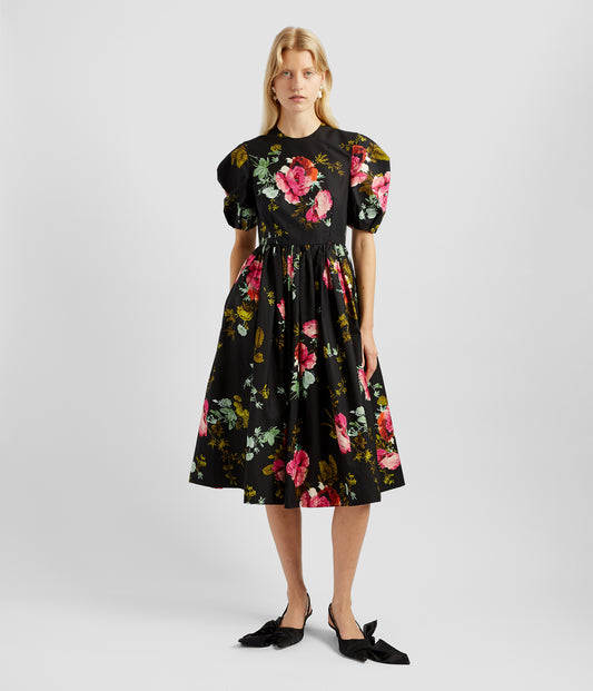 Midi aline dress with a fitted bodice, puff sleeves and voluminous aline midi skirt. The fabric is black with bold fuschia blooms. 