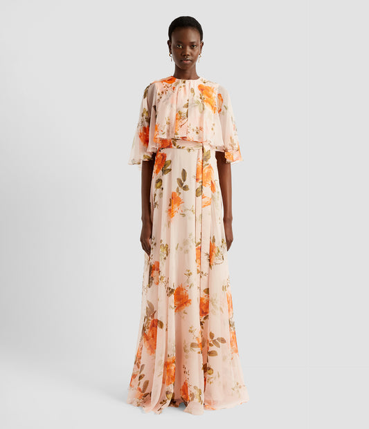 An elegant dress with a cape overlay from designer ERDEM. The floor length dress is crafted in light pink rose print silk voile. It's feminine and striking with the cape addition. 
