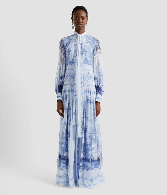 Blouson long dress in blue and white toile de jouy print. The blouson long dress has a gathered tie neck, blouson sleeves and a drop waist.  