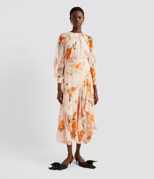 Asymmetrical midi skirt in light pink silk with an orange rose print. The tiered skirt is asymmetric with one ruffle sitting higher on the skirt. 