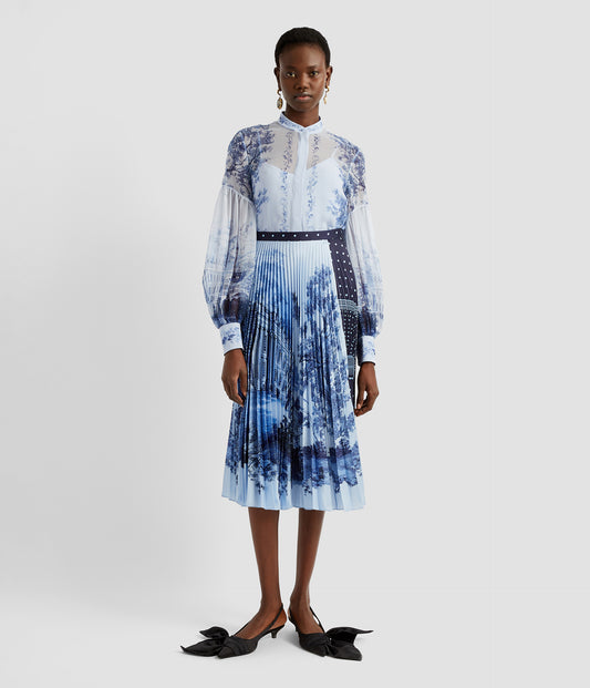 A blouson blouse by designer Erdem. Made from a lightweight silk voile that's sheer and featuring a stand collar, this blouson sleeve blouse is a timeless classic. Worn here with a matching pleated midi skirt. 
