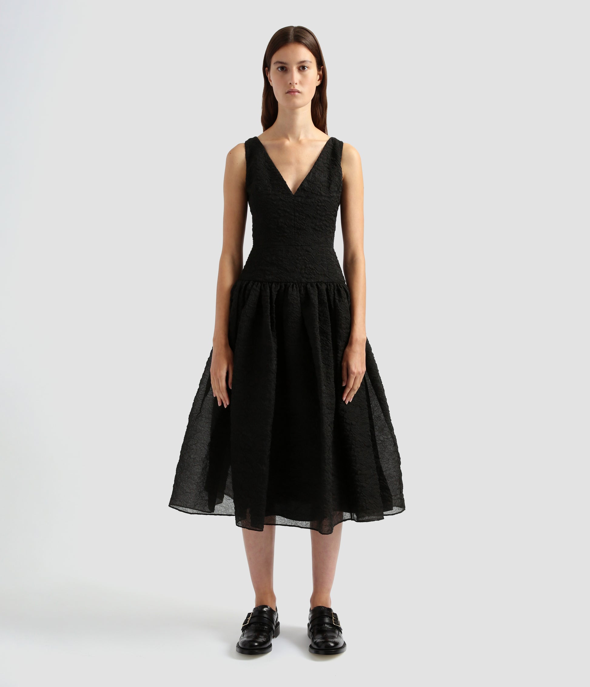 A stunning black organza dress made from black organza cloque with a textured surface. This dress with organza, is sleeveless with a cinched waist, full skirt and low v-neckline. 