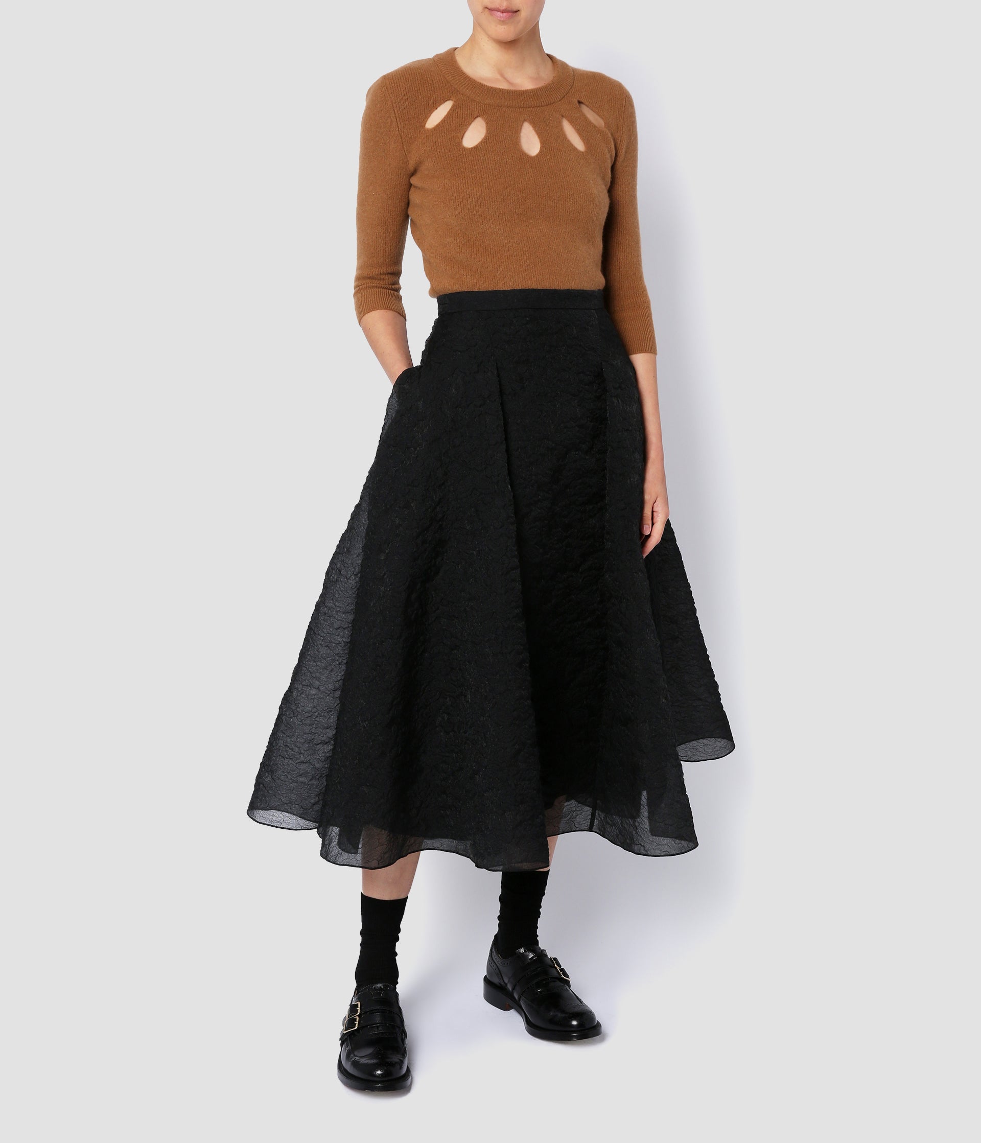 A flared, midi-length volume skirt in black organza cloque. The skirt is fitted at the waist, with pockets and large pleats to create the dramatic flared silhouette. 