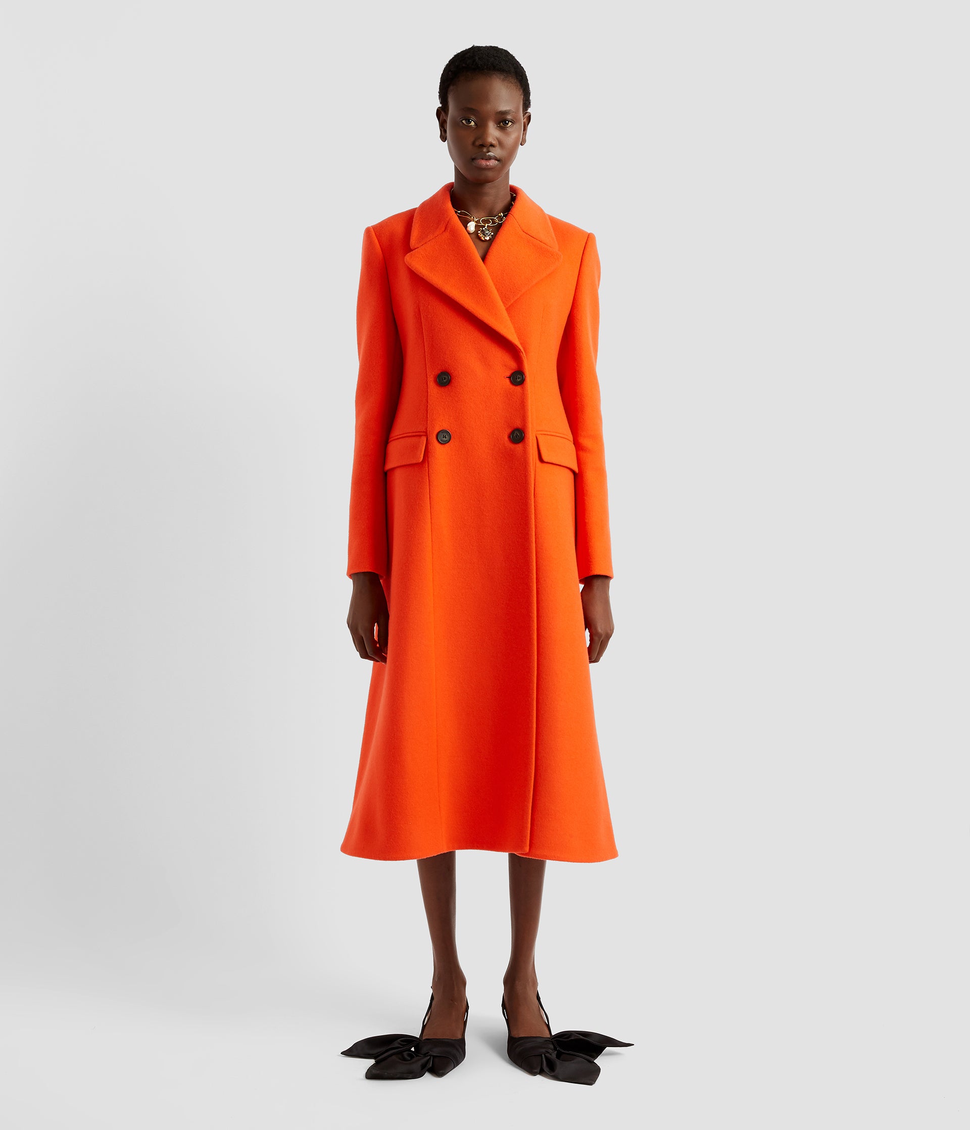 A red wool double breasted coat with an a-line flared silhouette. The coat is made from wool and cashmere with flap pockets and a structured shoulder. 