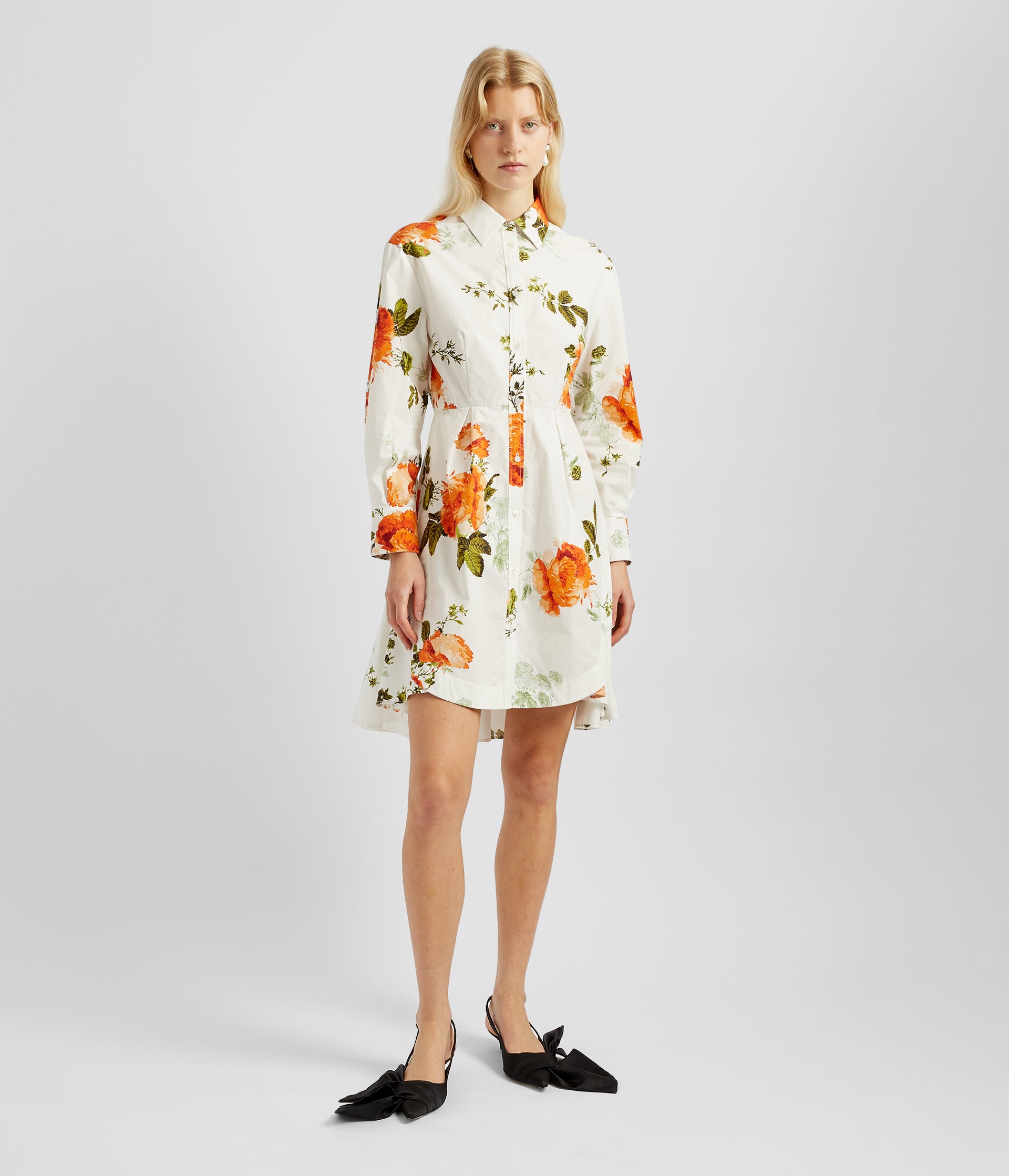 Button down mini dress is a modern twist on a men's shirt. Made from white cotton poplin with a large orange and green rose print and a button down front. 