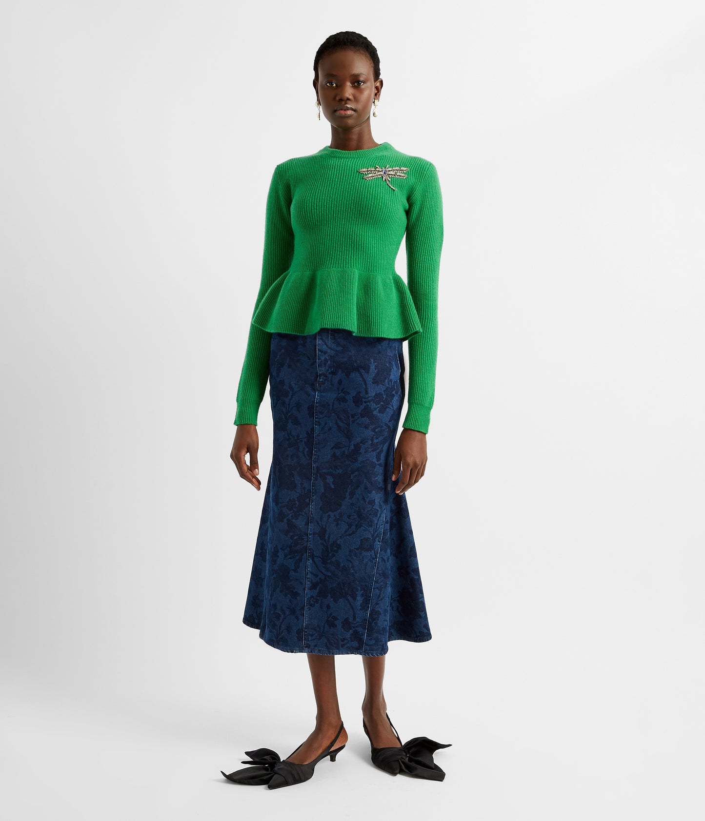 A green peplum jumper crafted from soft ribbed wool knit. The peplum jumper is elegant and modern and features a beaded dragonfly on the chest. 