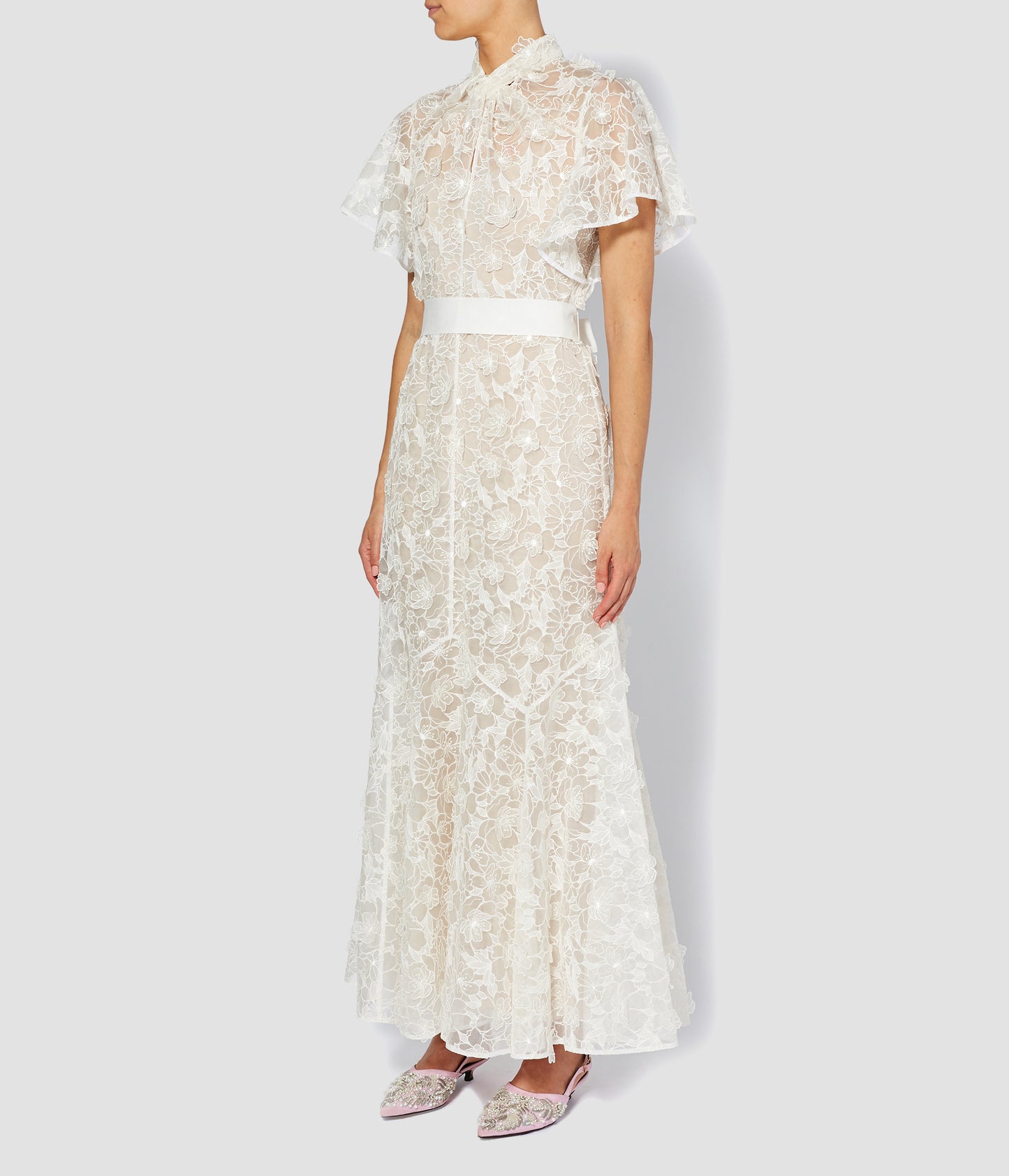 The Celestina wedding dress by designer ERDEM. Made from 3D organza with a floral pattern, this modern wedding dress has a panelled skirt, cape-style sleeves and a waist belt. 