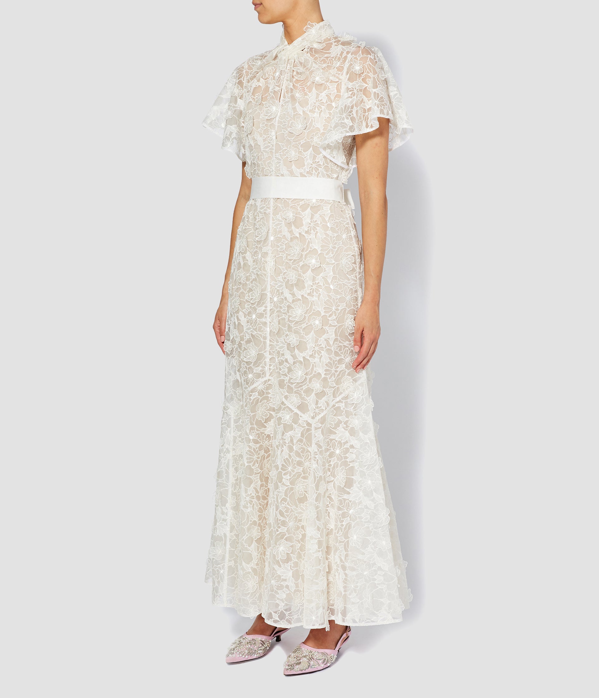 The Celestina wedding dress by designer ERDEM. Made from 3D organza with a floral pattern, this modern wedding dress has a panelled skirt, cape-style sleeves and a waist belt. 